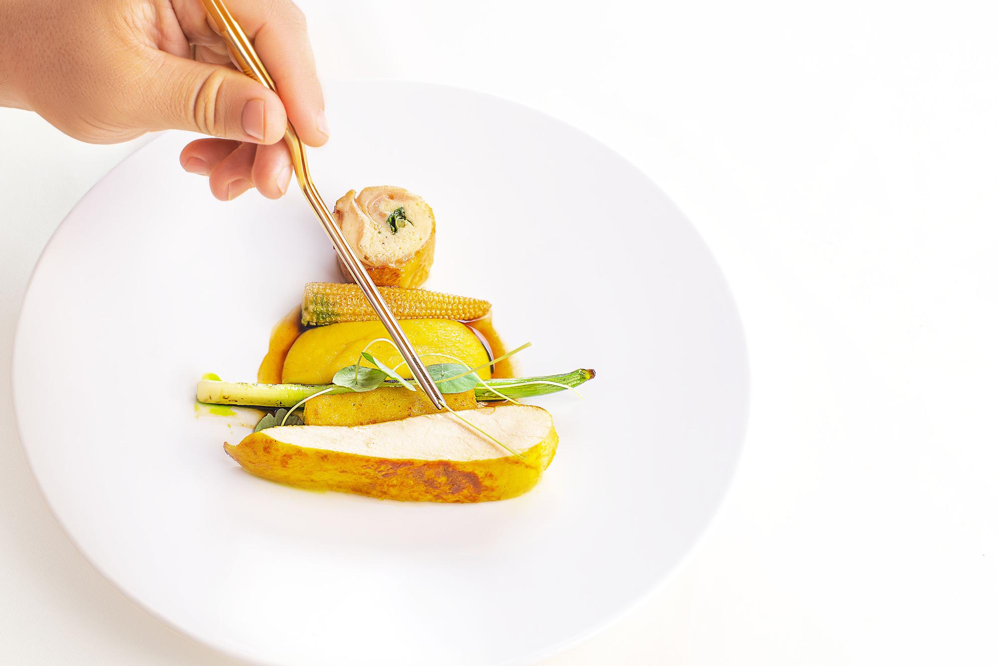 Close-up of hands garnishing a dish